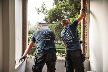 Deux installers de Reynaers Aluminium démontent d’anciennes fenêtres sur place.