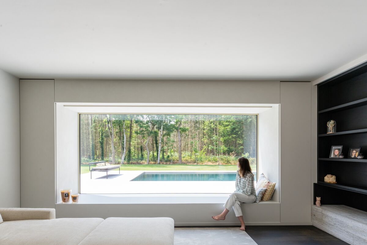 Une femme est assise sur le rebord d'une fenêtre en aluminium