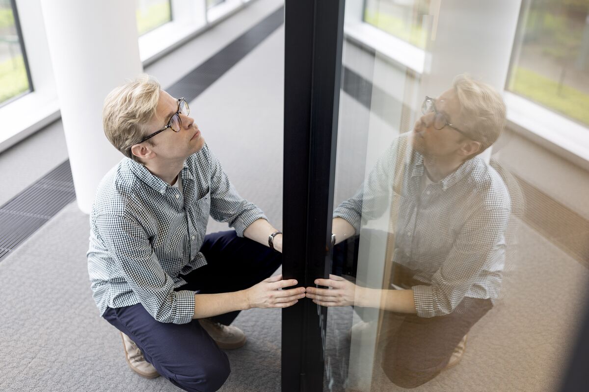 Homme avec des lunettes tenant un profil en aluminium noir.