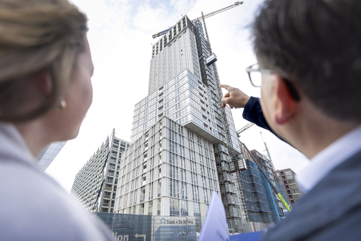 Un homme et une femme lèvent les yeux vers un gratte-ciel gris en construction.
