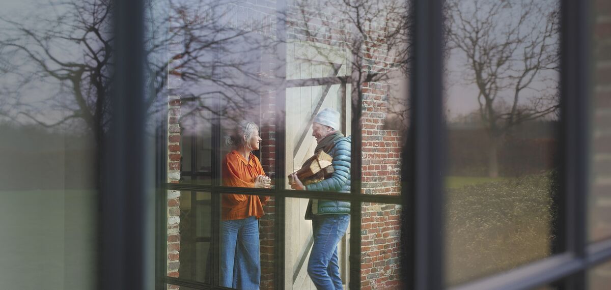 Man en vrouw praten met elkaar naast aluminium raam