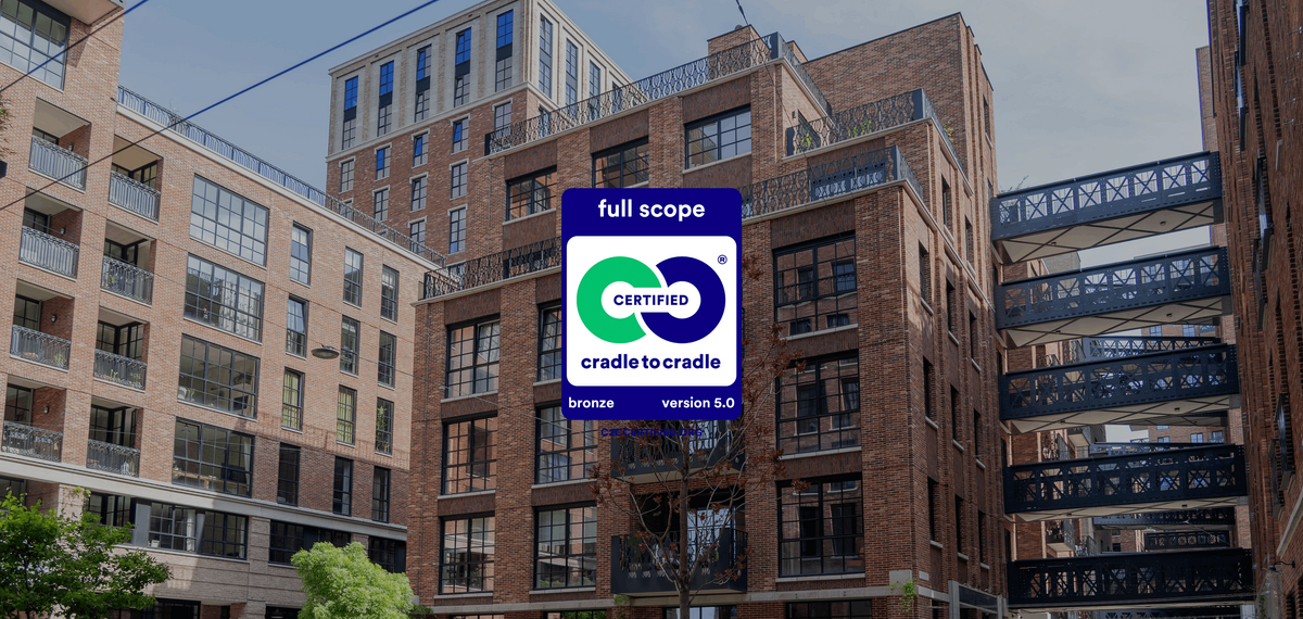 Le logo Cradle to Cradle devant des immeubles de grande hauteur en briques rouges.
