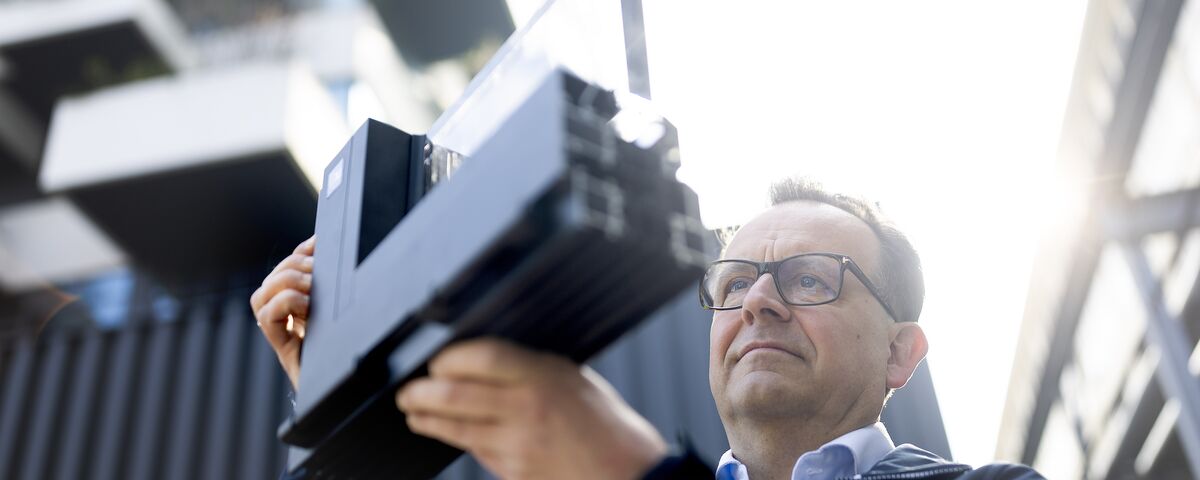 Homme avec des lunettes regardant de près l’échantillon d’angle en aluminium.