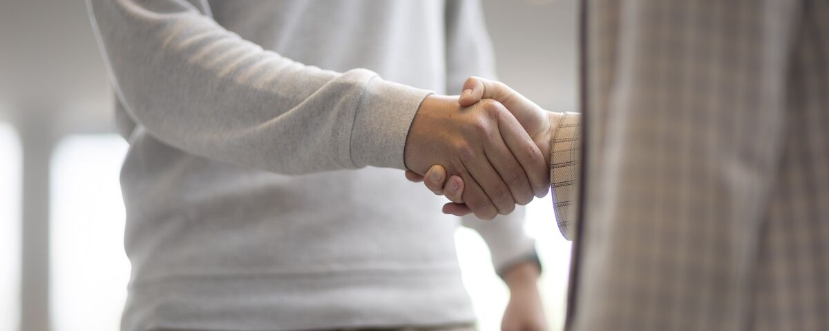 Un homme et une femme se serrant la main dans un immeuble de bureaux.