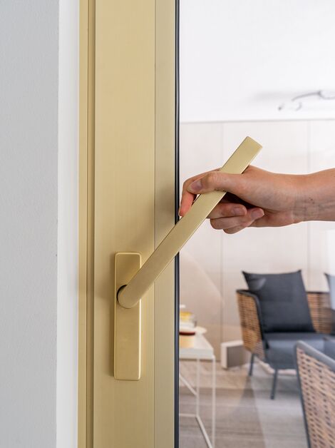 Goudkleurig aluminium schuifraam met deurkruk
