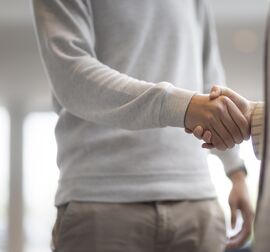 Un homme et une femme se serrant la main dans un immeuble de bureaux.