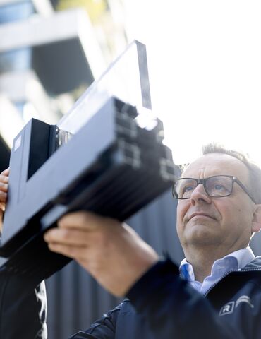 Homme avec des lunettes regardant de près un échantillon d’angle en aluminium.