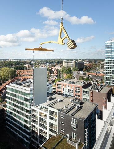 Panneau de construction modulaire soulevé à côté d’un gratte-ciel.