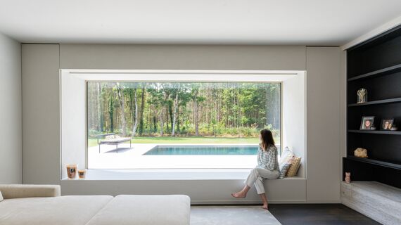 Une femme est assise sur le rebord d'une fenêtre en aluminium
