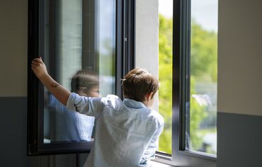Kind opent Reynaers Aluminium raam en kijkt naar buiten