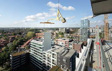 Panneau de construction modulaire soulevé à côté d’un gratte-ciel.